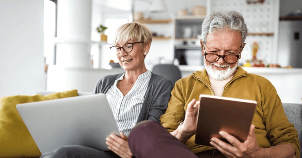 Man and woman using devices at home on sofa