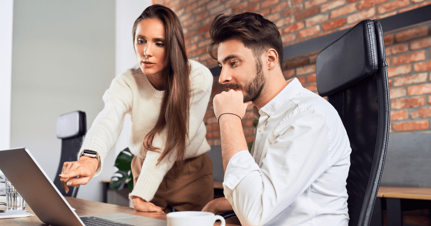 Colleagues in office looking at laptop after phishing attempt together