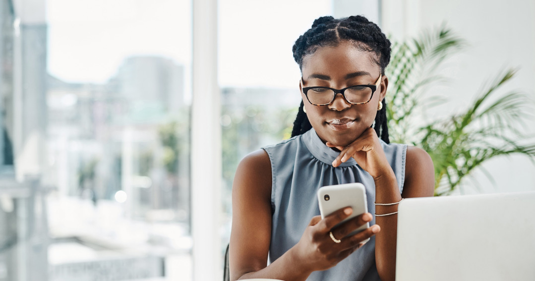 Female professional in white minimal office looking at phone at desk