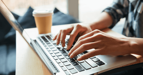 Hands typing on laptop keyboard on train