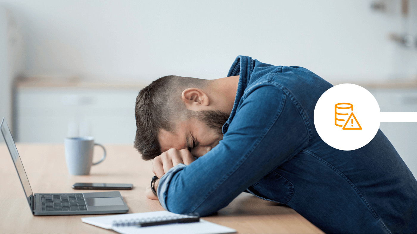 Man with head and arms on desk in front of laptop