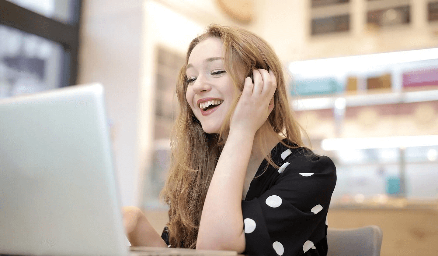 Woman using laptop in kitchen and smiling