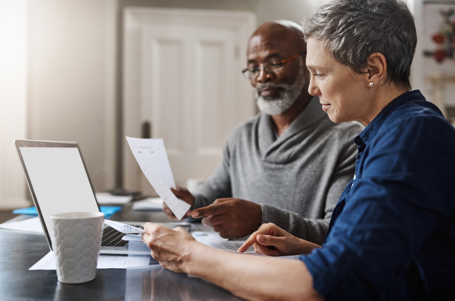 man and woman doing their finances next to laptop