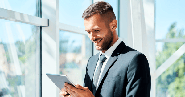 man in a suit smiling and using laptop